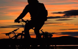 Radfahrer am Seeufer im Fränkischen Seenland bei Sonnenuntergang
